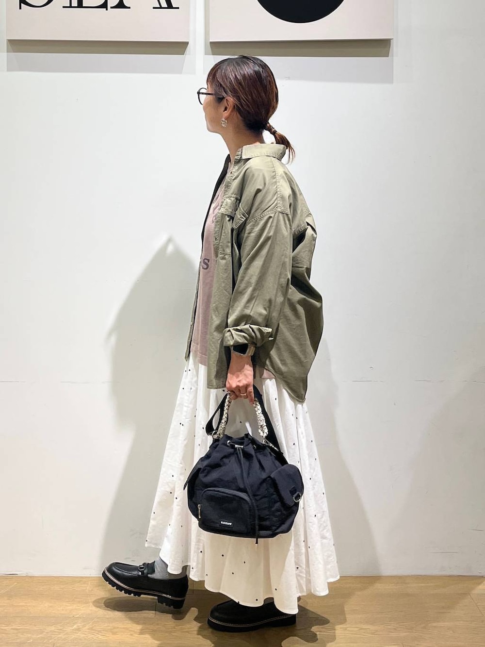 グリーン系のシャツ/ブラウス、ブラウン系のTシャツ/カットソー、ホワイト系のスカートを着用したレディースの秋コーディネートの2枚目の写真