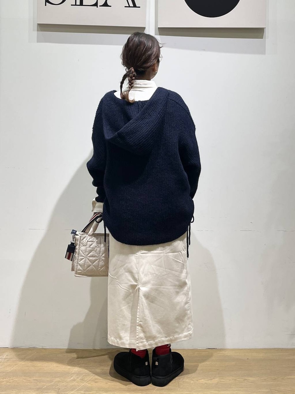 ホワイト系のショルダーバッグ、ベージュ系のスカート、ブラック系のブーツを着用したレディースの秋コーディネートの3枚目の写真