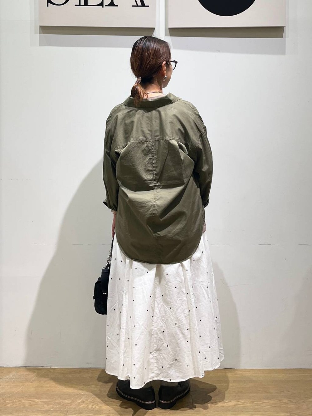 グリーン系のシャツ/ブラウス、ブラウン系のTシャツ/カットソー、ホワイト系のスカートを着用したレディースの秋コーディネートの3枚目の写真