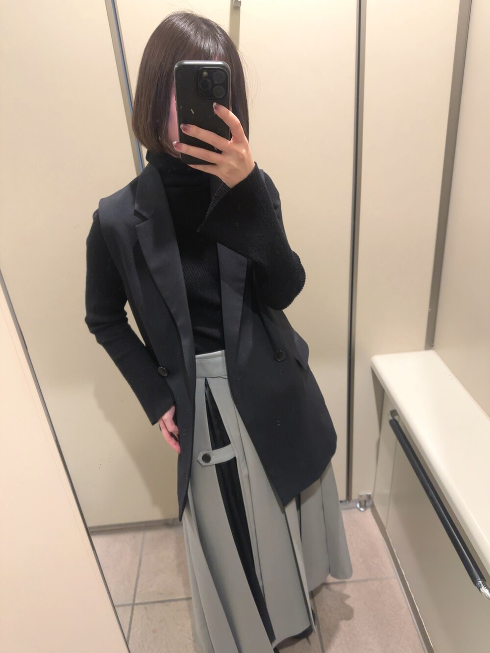 ブルー系のテーラードジャケット、グレー系のスカート、ブラック系のニット/セーターを着用したレディースの秋コーディネートの2枚目の写真