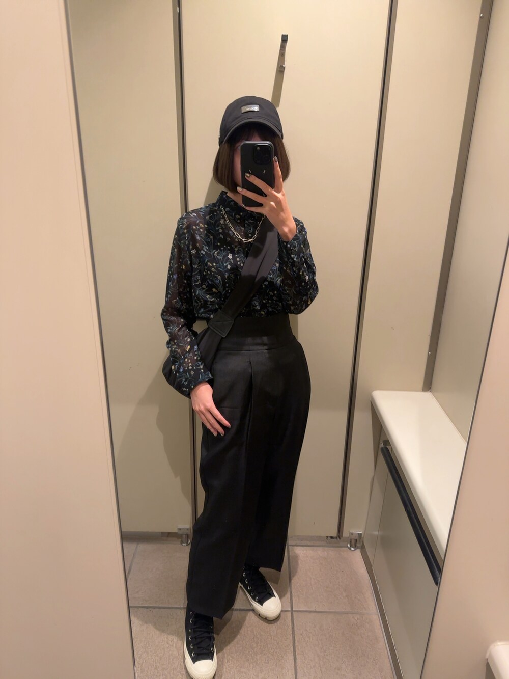 ブラック系のスラックス、ブラック系のスニーカー、ブラック系のショルダーバッグを着用したレディースの秋コーディネートの2枚目の写真