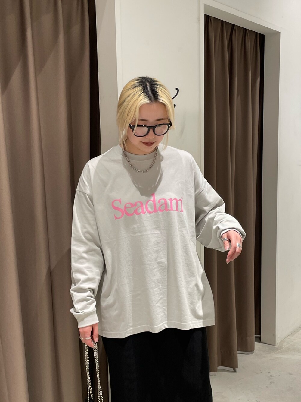 グレー系のTシャツ/カットソー、ブラック系のスカート、ブラック系のショルダーバッグを着用したレディースの春コーディネートの4枚目の写真