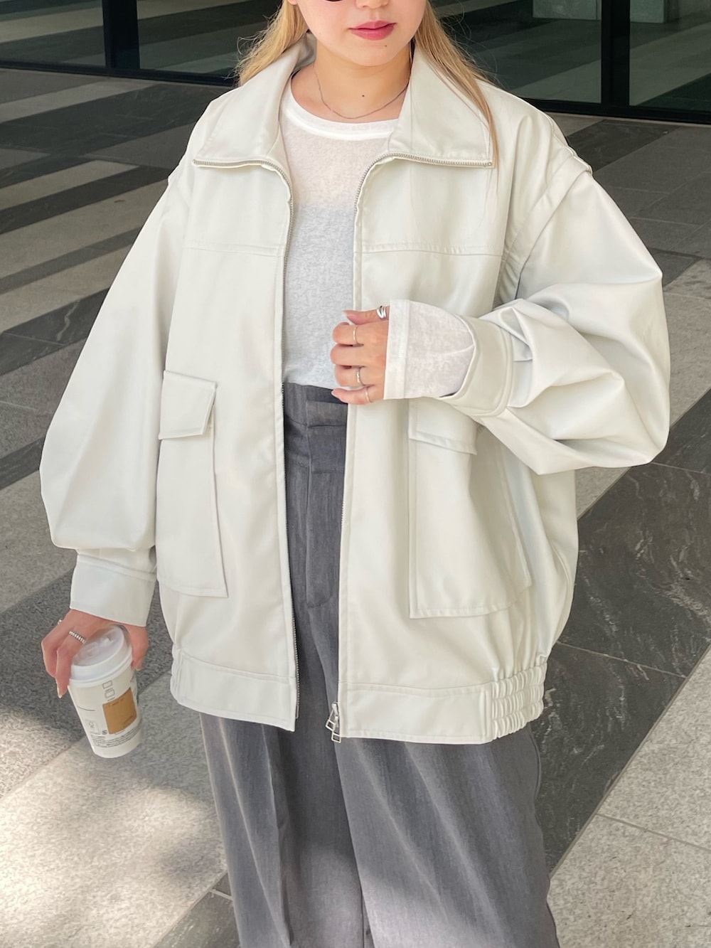 ホワイト系のジャケット/アウター、ホワイト系のTシャツ/カットソー、グレー系のスラックスを着用したレディースの秋コーディネートの3枚目の写真