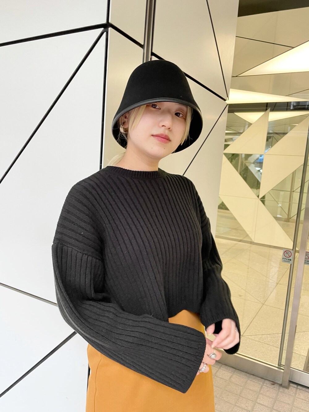 ブラック系のニット/セーター、イエロー系のスカート、ブラック系のブーツを着用したレディースの秋コーディネートの2枚目の写真