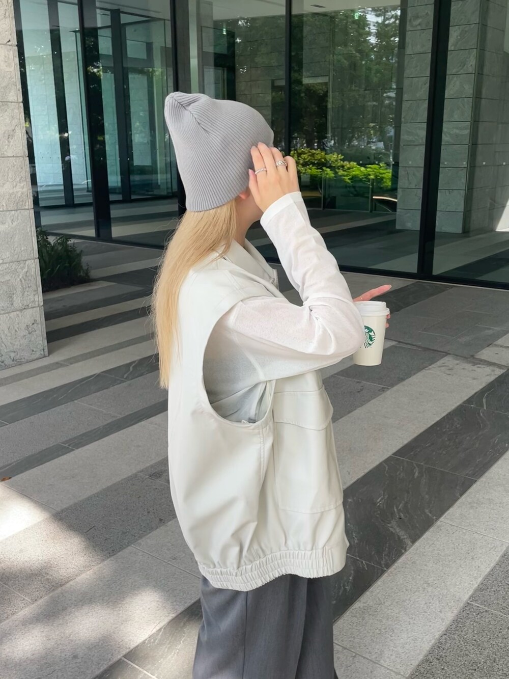 ホワイト系のジャケット/アウター、ホワイト系のTシャツ/カットソー、グレー系のスラックスを着用したレディースの秋コーディネートの8枚目の写真