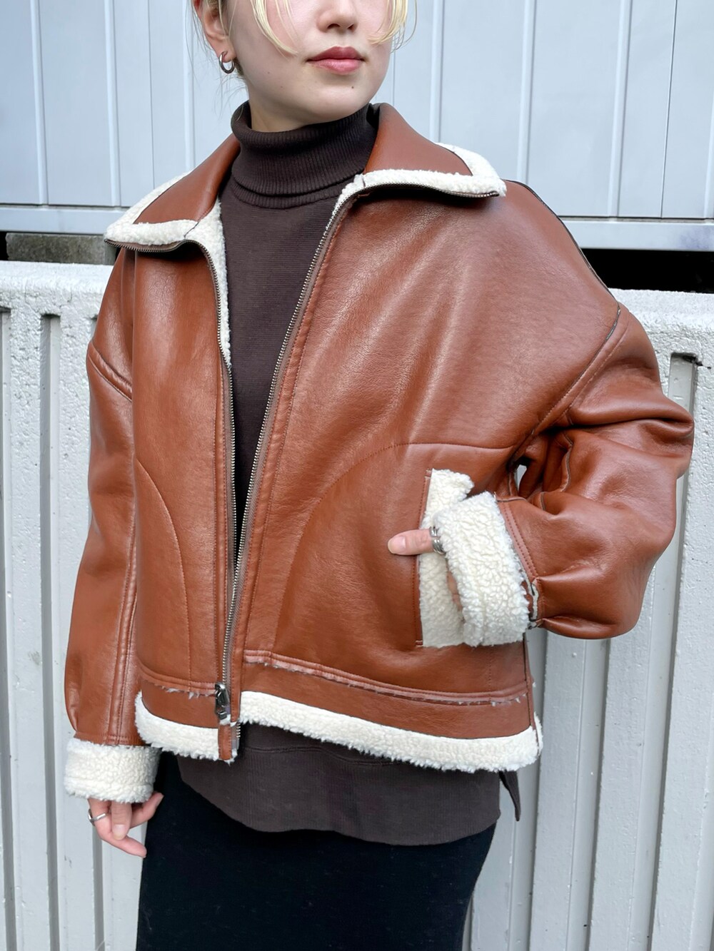 ブラウン系のブルゾン、ブラック系のスカート、ブラック系のブーツを着用したレディースの秋コーディネートの4枚目の写真