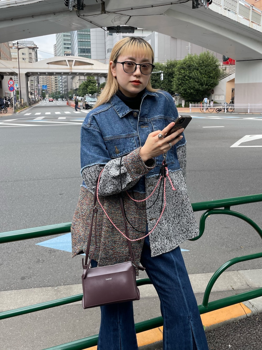 ブルー系のデニムジャケット、ブルー系のデニムパンツ、パープル系のショルダーバッグを着用したレディースの秋コーディネートの2枚目の写真