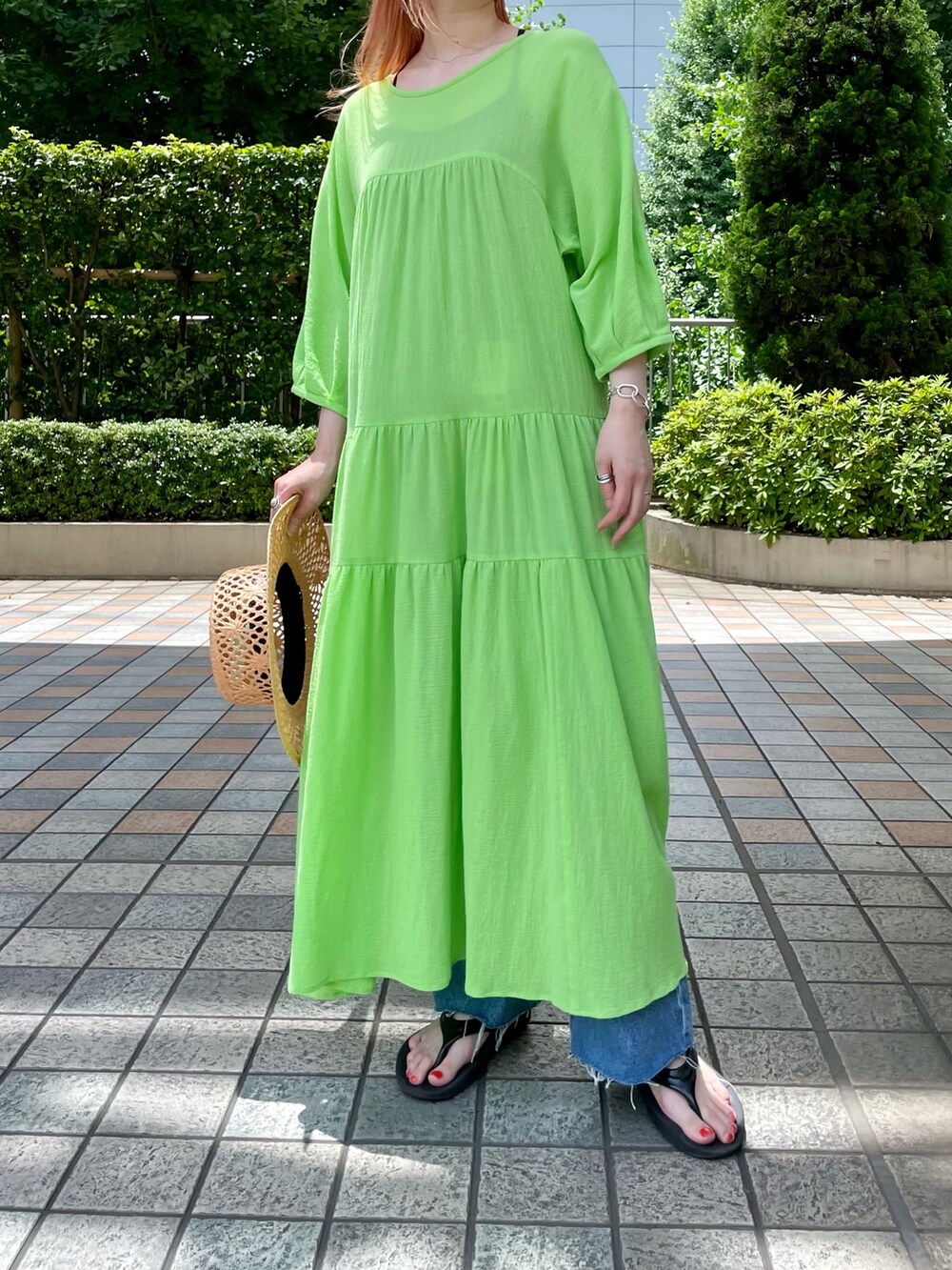 グリーン系のワンピース、ブルー系のデニムパンツ、ベージュ系のトートバッグを着用したレディースの夏コーディネートの3枚目の写真