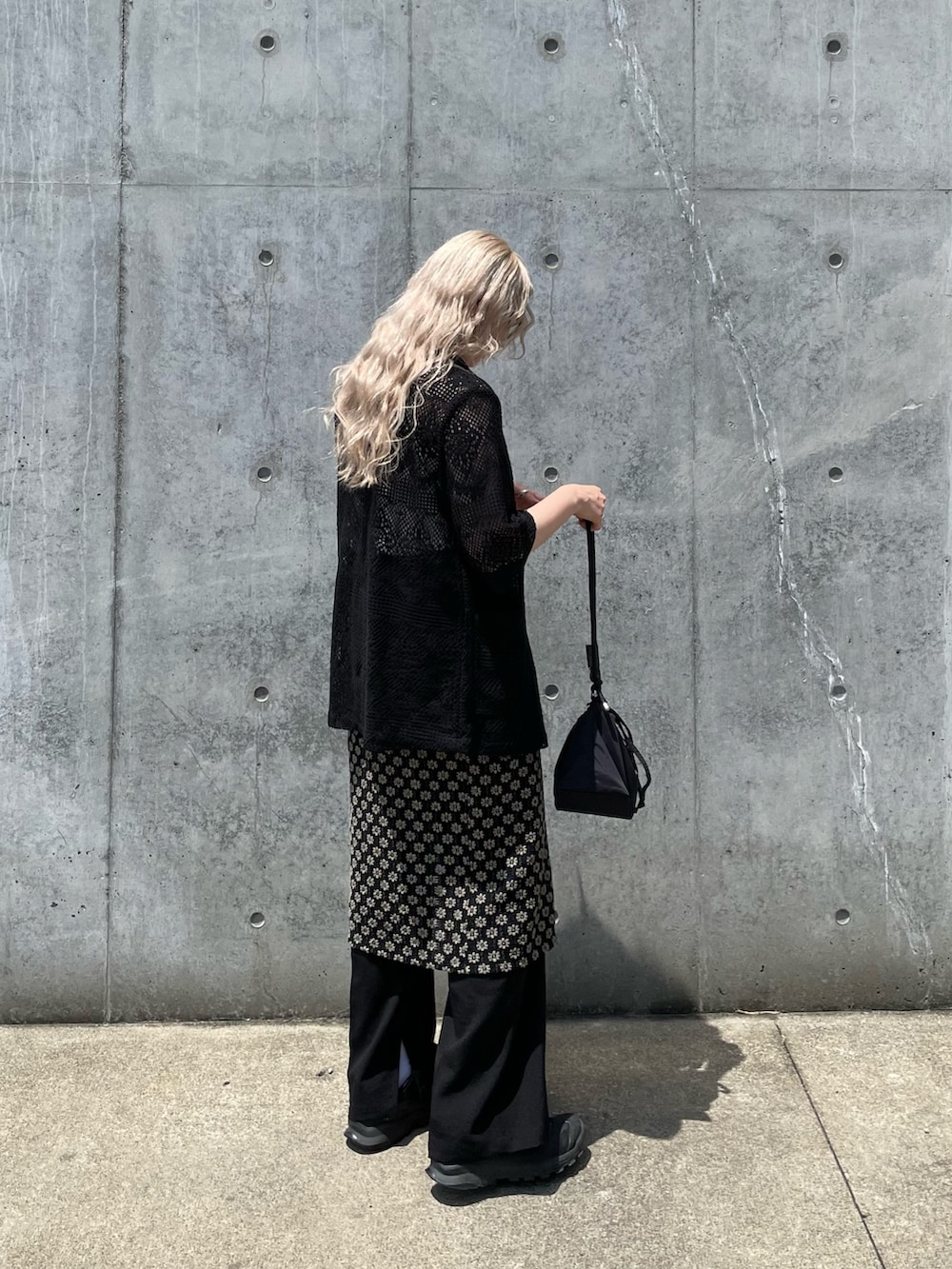 ブラック系のテーラードジャケット、ブラック系のスカート、ブラック系のショルダーバッグを着用したレディースの夏コーディネートの2枚目の写真