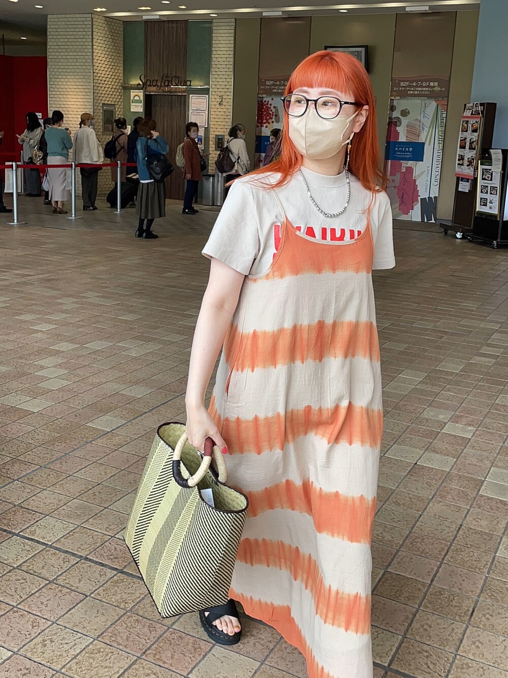 オレンジ系のワンピース、ベージュ系のTシャツ/カットソー、ブラック系のかごバッグを着用したレディースの春コーディネートの3枚目の写真