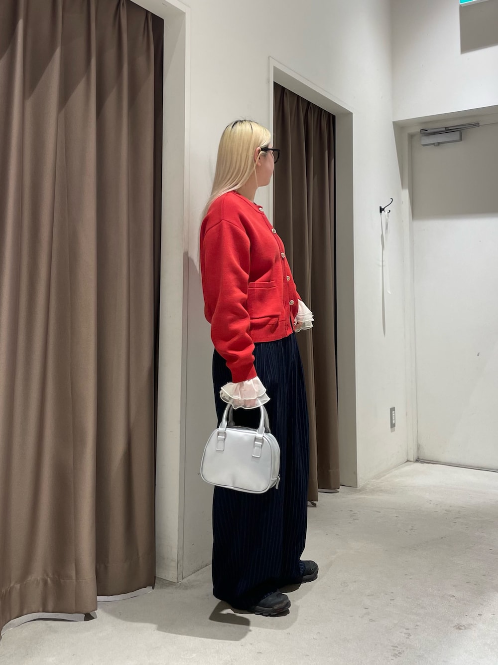 レッド系のカーディガン/ボレロ、イエロー系のTシャツ/カットソー、ブルー系のスラックスを着用したレディースの冬コーディネートの9枚目の写真