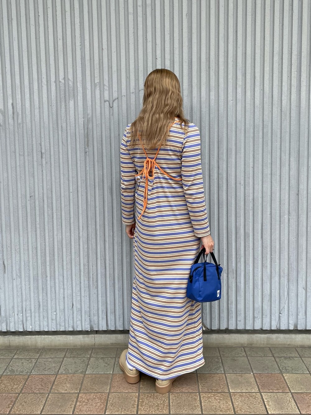 オレンジ系のワンピース、ブルー系のトートバッグを着用したレディースの秋コーディネートの2枚目の写真