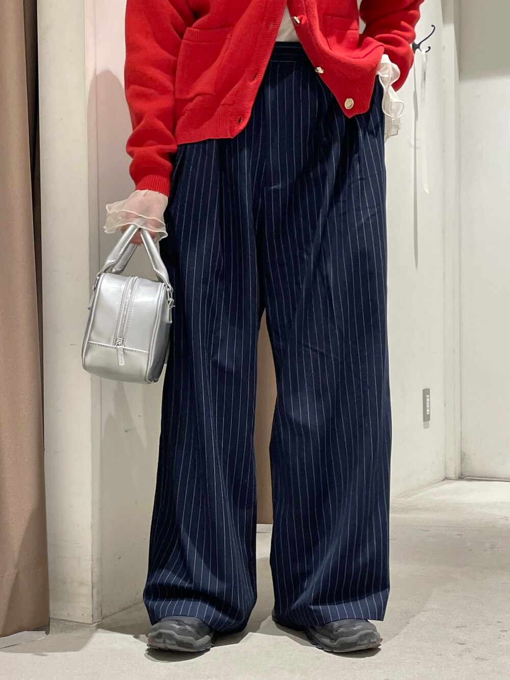 レッド系のカーディガン/ボレロ、イエロー系のTシャツ/カットソー、ブルー系のスラックスを着用したレディースの冬コーディネートの6枚目の写真