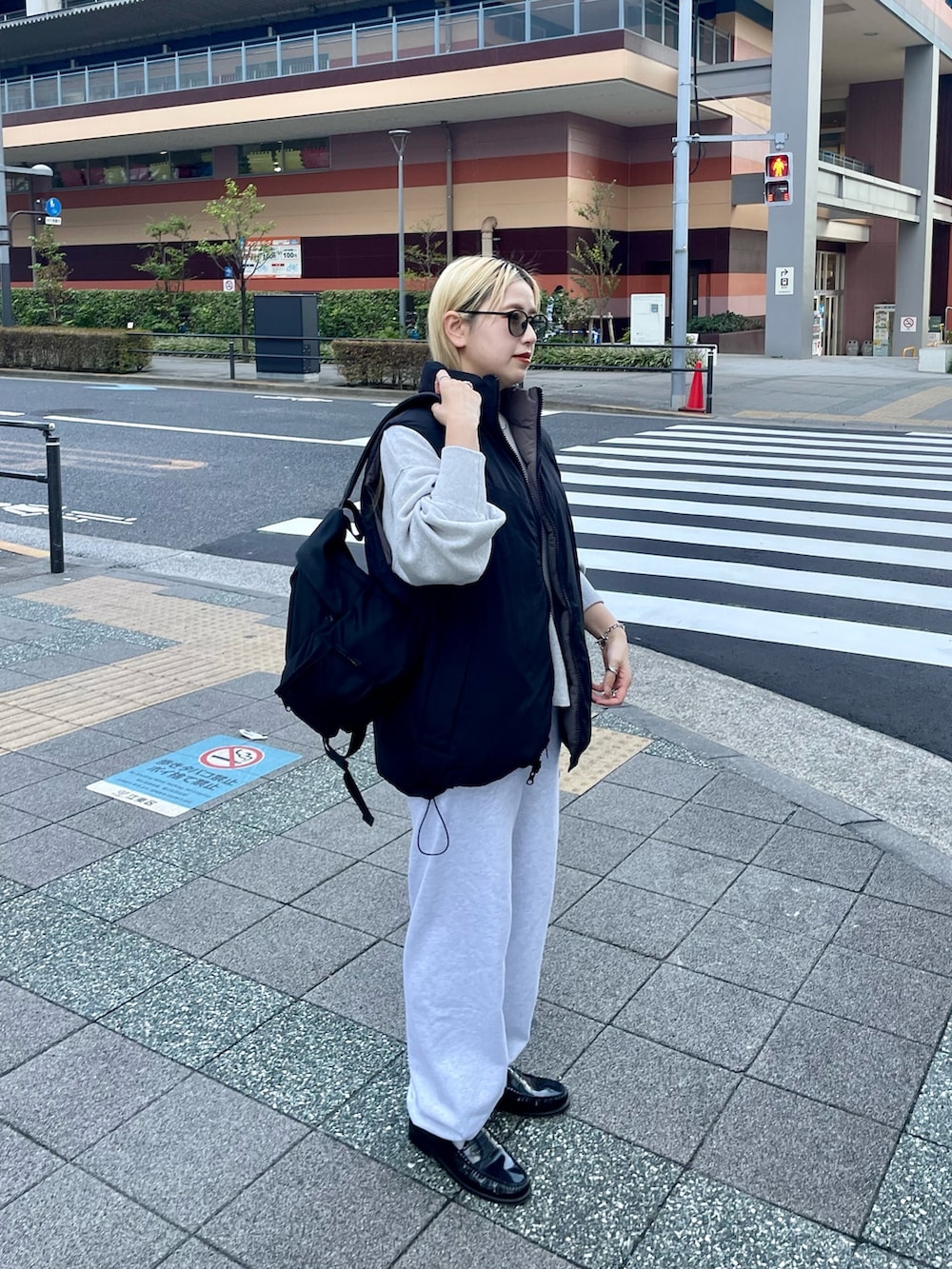 ブラック系のダウンベスト、ホワイト系のニット/セーター、グレー系のスウェットパンツを着用したレディースの冬コーディネートの2枚目の写真