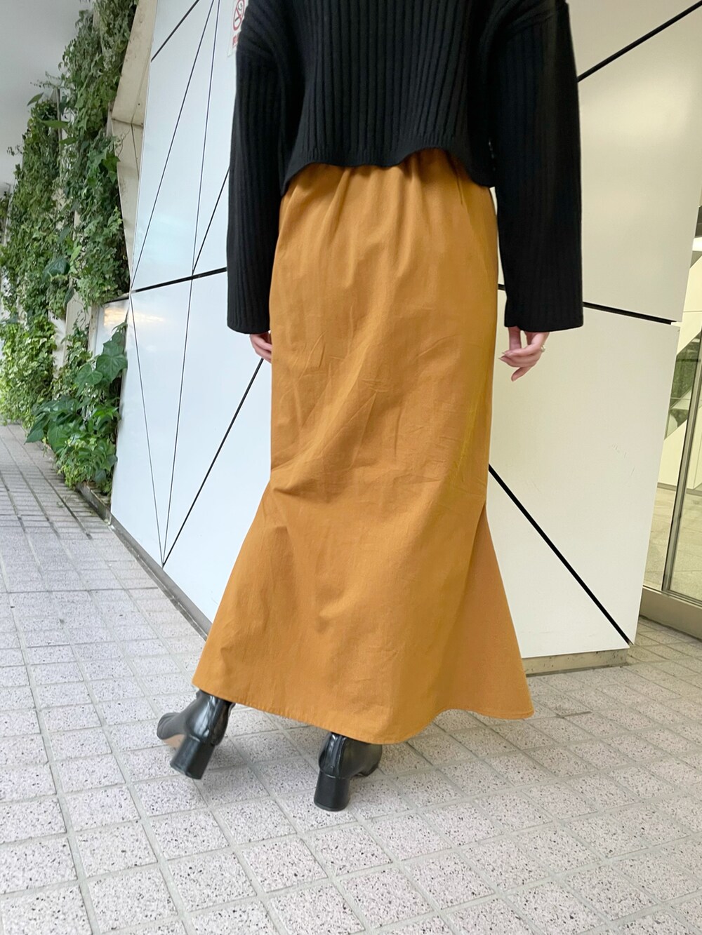 ブラック系のニット/セーター、イエロー系のスカート、ブラック系のブーツを着用したレディースの秋コーディネートの5枚目の写真