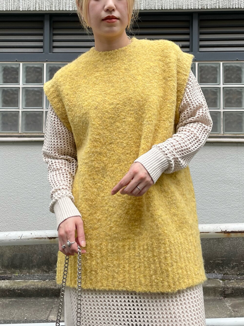 イエロー系のベスト、ブラック系のショルダーバッグ、ホワイト系のワンピースを着用したレディースの秋コーディネートの3枚目の写真