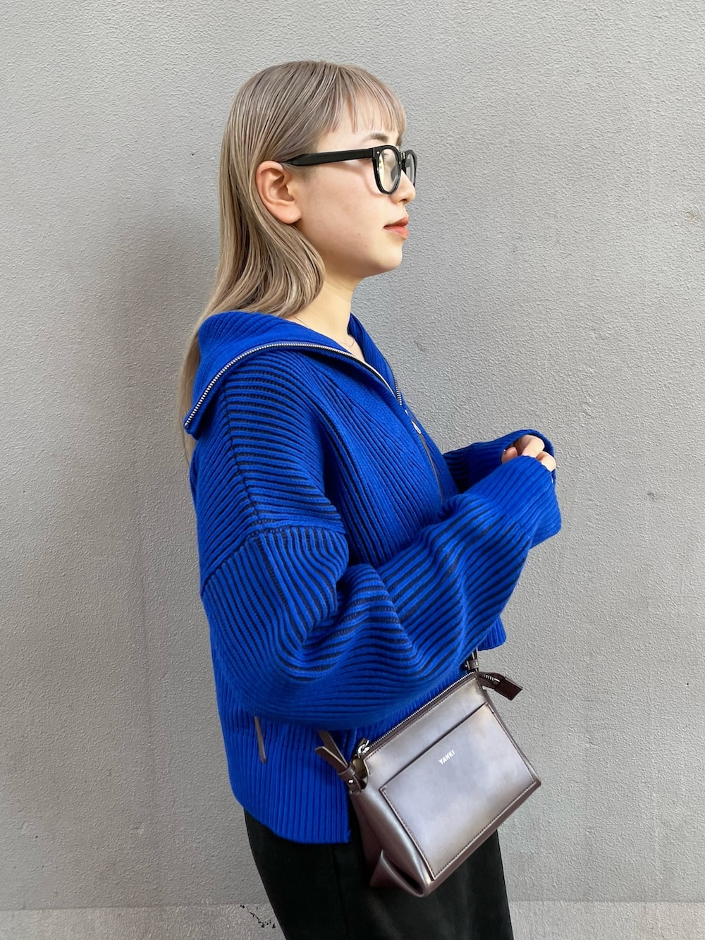 ブルー系のニット/セーター、ブラック系のワンピース、ブラック系のブーツを着用したレディースの秋コーディネートの4枚目の写真