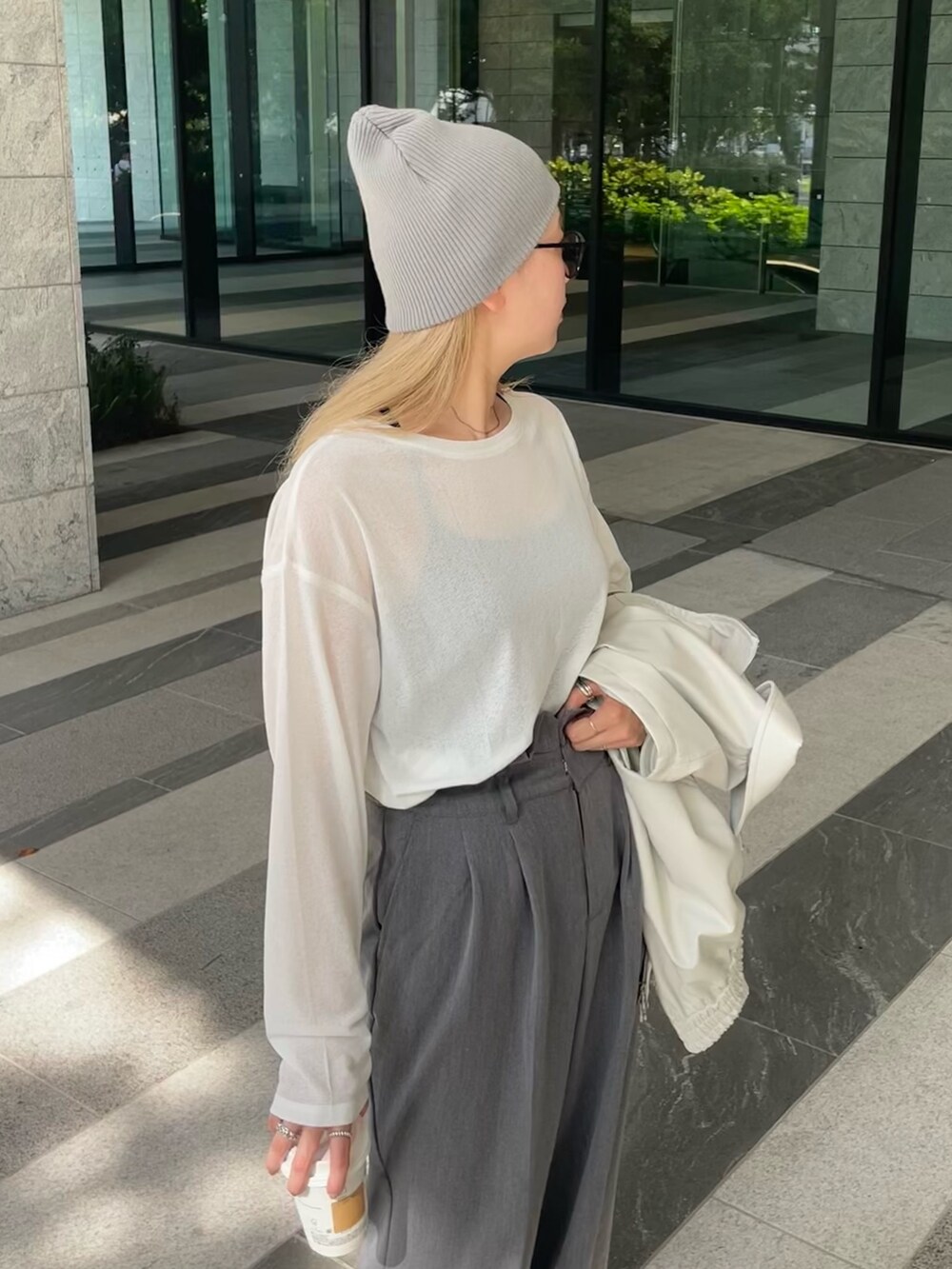 ホワイト系のジャケット/アウター、ホワイト系のTシャツ/カットソー、グレー系のスラックスを着用したレディースの秋コーディネートの9枚目の写真