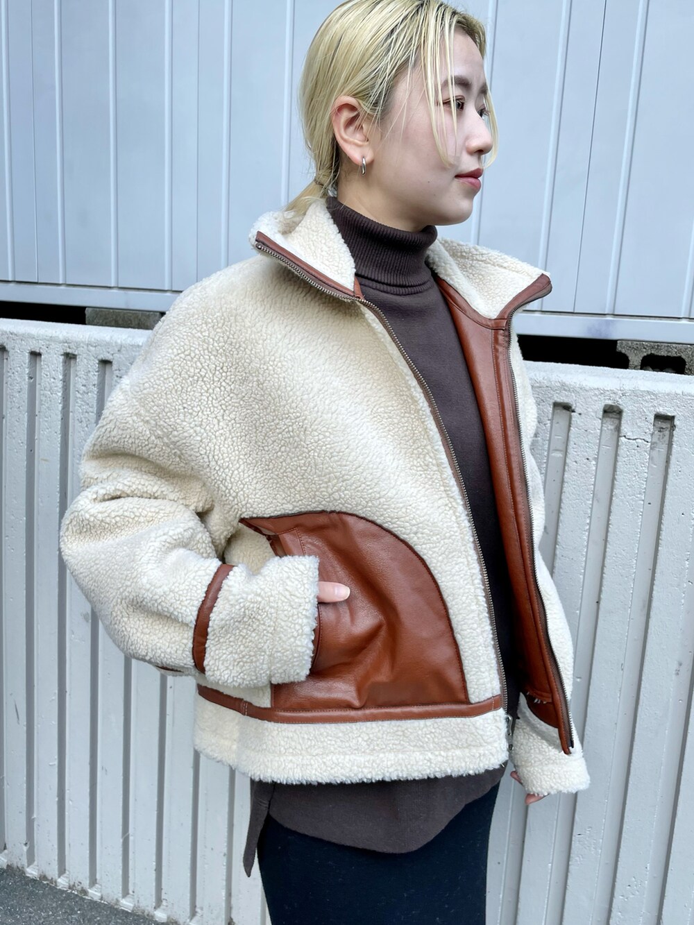 ブラウン系のブルゾン、ブラック系のスカート、ブラック系のブーツを着用したレディースの秋コーディネートの2枚目の写真