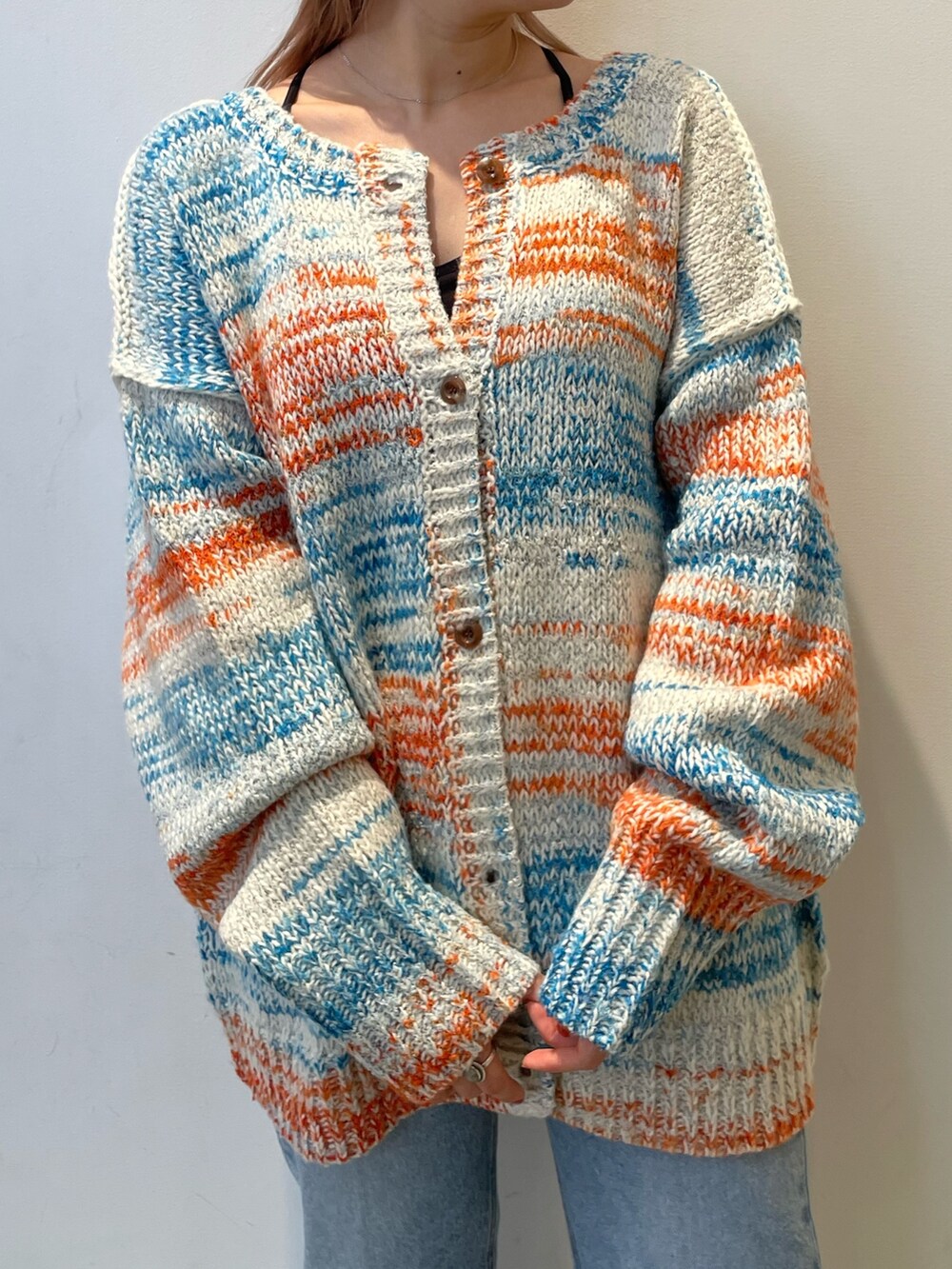 ホワイト系のカーディガン/ボレロ、ブラック系のバッグ、ブルー系のデニムパンツを着用したレディースの秋コーディネートの4枚目の写真