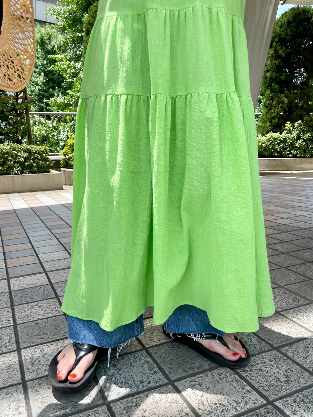 グリーン系のワンピース、ブルー系のデニムパンツ、ベージュ系のトートバッグを着用したレディースの夏コーディネートの5枚目の写真