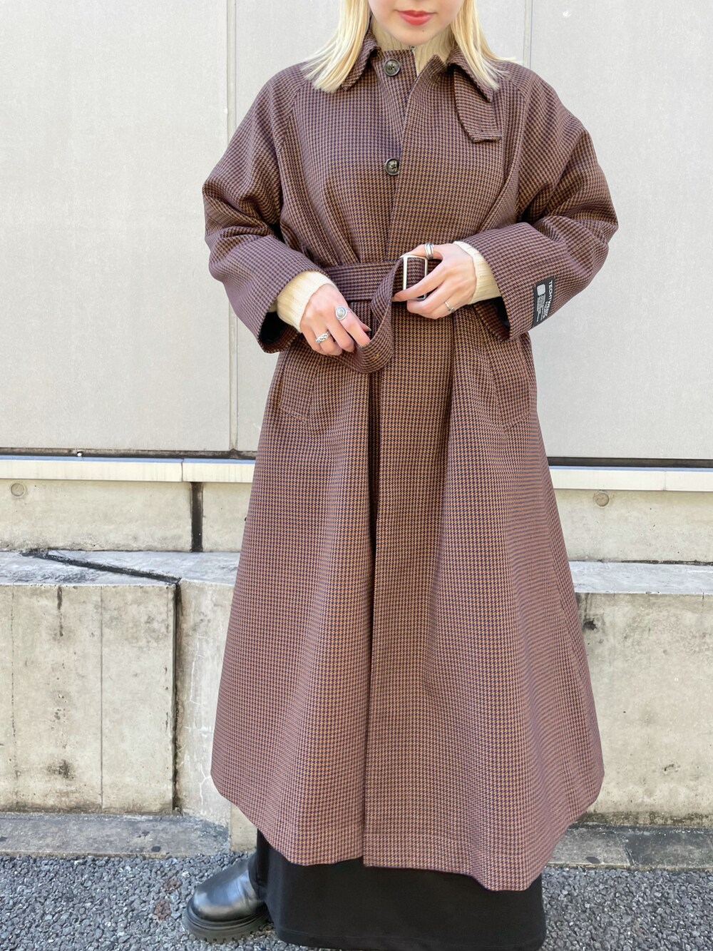 ブルー系のステンカラーコート、ホワイト系のニット/セーター、ブラック系のワンピースを着用したレディースの秋コーディネートの5枚目の写真