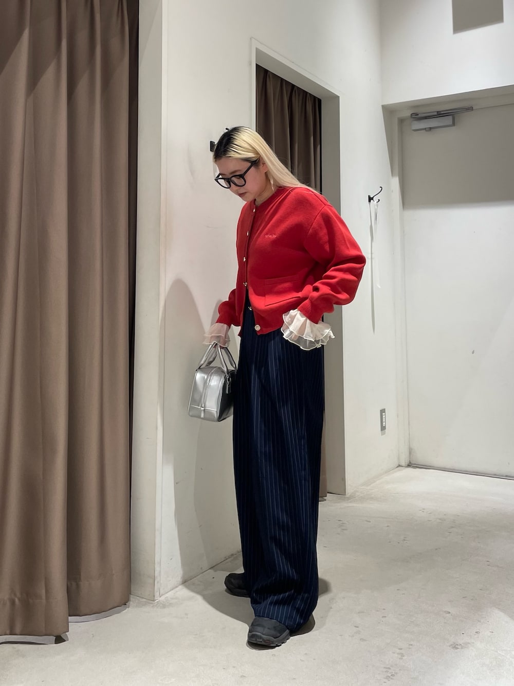 レッド系のカーディガン/ボレロ、イエロー系のTシャツ/カットソー、ブルー系のスラックスを着用したレディースの冬コーディネートの7枚目の写真