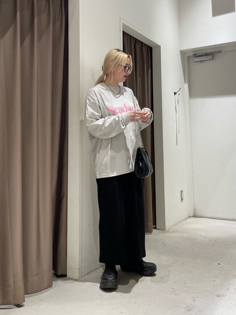 グレー系のTシャツ/カットソー、ブラック系のスカート、ブラック系のショルダーバッグを着用したレディースの春コーディネートの2枚目の写真