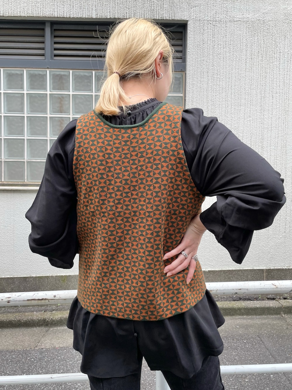 グリーン系のステンカラーコート、ブラウン系のベスト、ブラック系のシャツ/ブラウスを着用したレディースの秋コーディネートの5枚目の写真