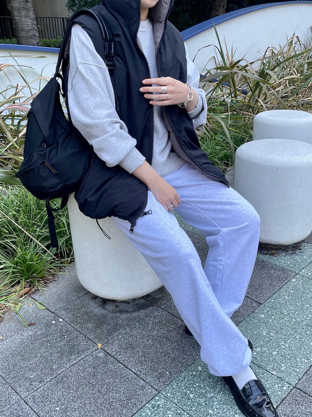 ブラック系のダウンベスト、ホワイト系のニット/セーター、グレー系のスウェットパンツを着用したレディースの冬コーディネートの8枚目の写真