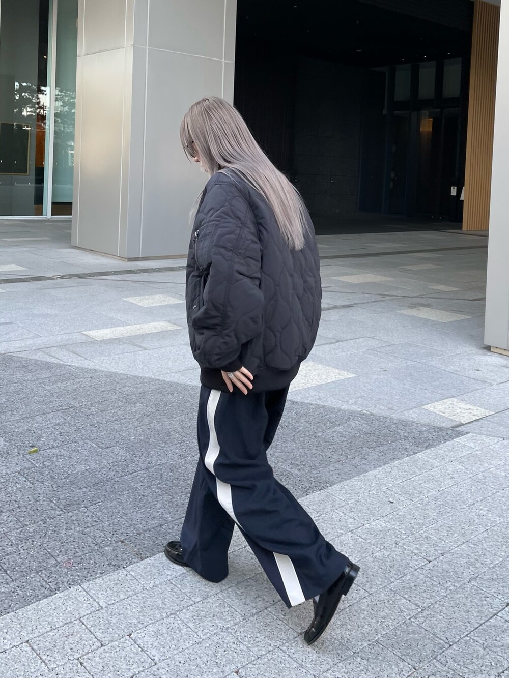 ブラック系のジャケット/アウター、ブラック系のニット/セーター、ブルー系のスラックスを着用したレディースの冬コーディネートの3枚目の写真