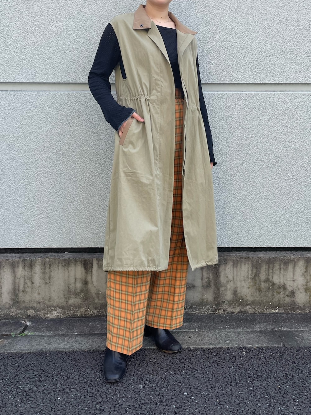 グリーン系のノーカラーコート、オレンジ系のスラックスを着用したレディースの夏コーディネートの4枚目の写真