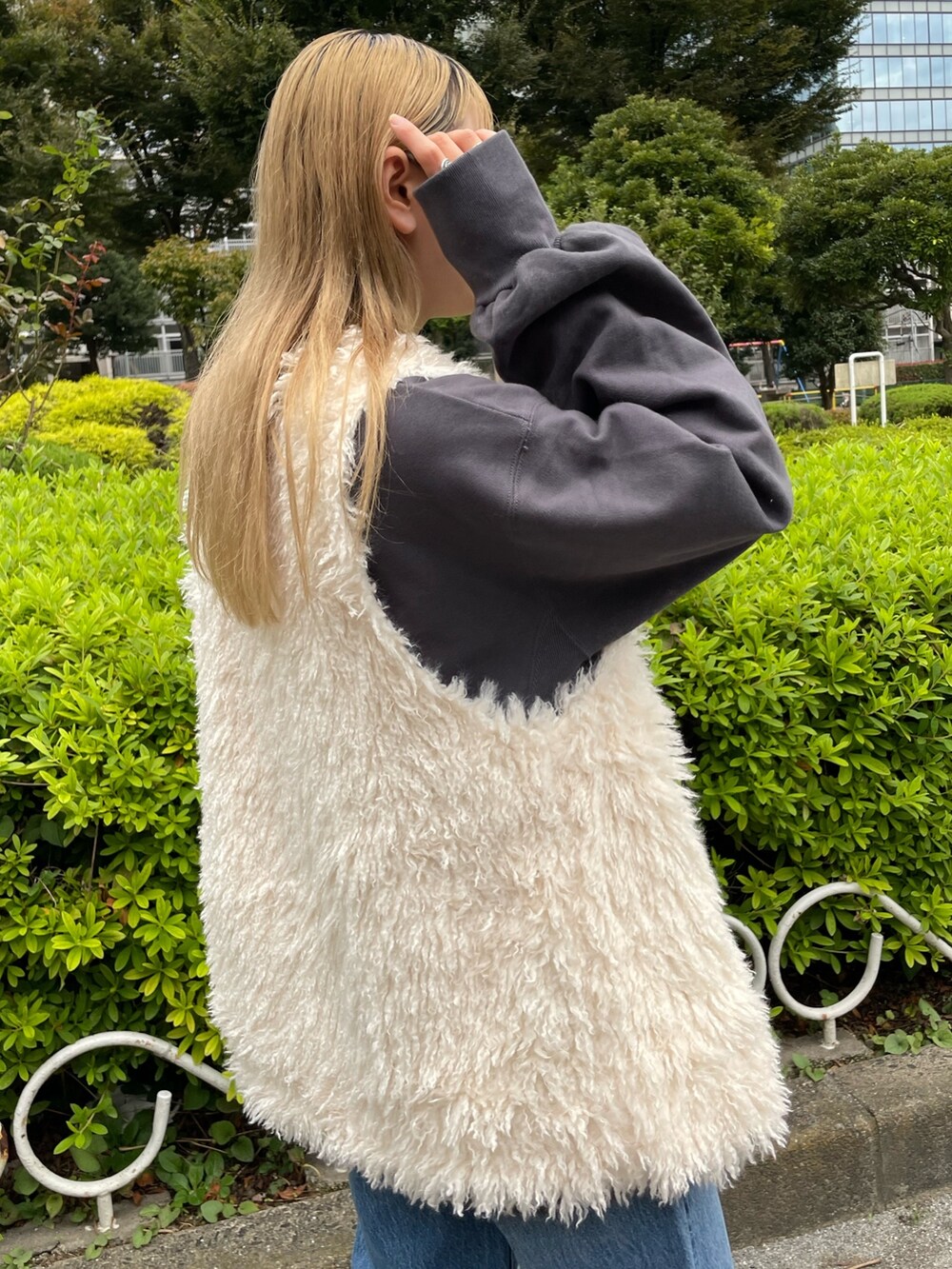 ホワイト系のベスト、グレー系のスウェット、ブルー系のデニムパンツを着用したレディースの秋コーディネートの6枚目の写真