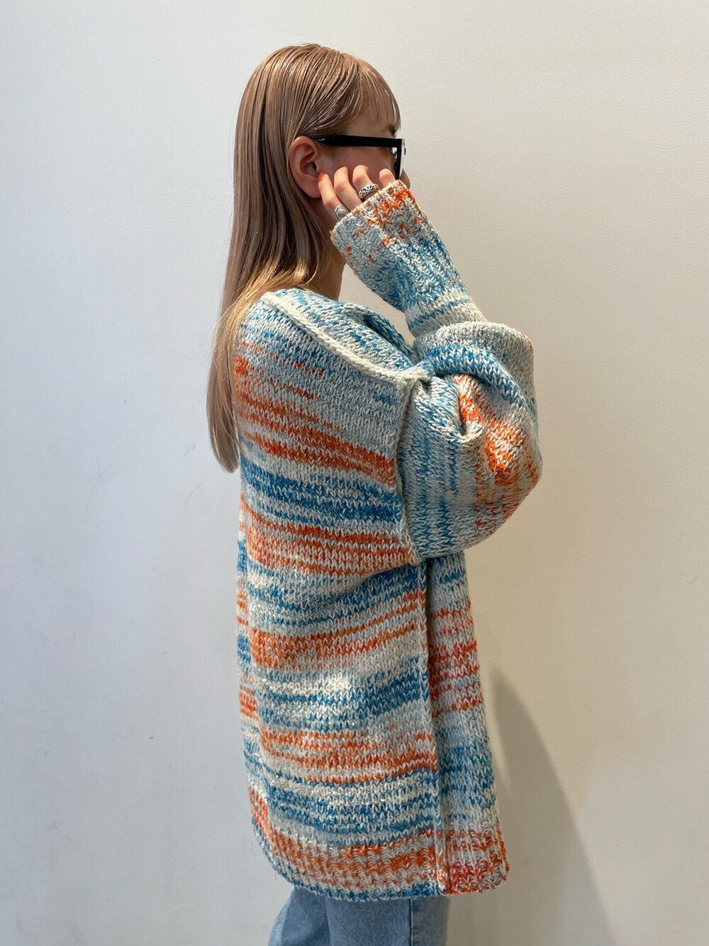 ホワイト系のカーディガン/ボレロ、ブラック系のバッグ、ブルー系のデニムパンツを着用したレディースの秋コーディネートの6枚目の写真