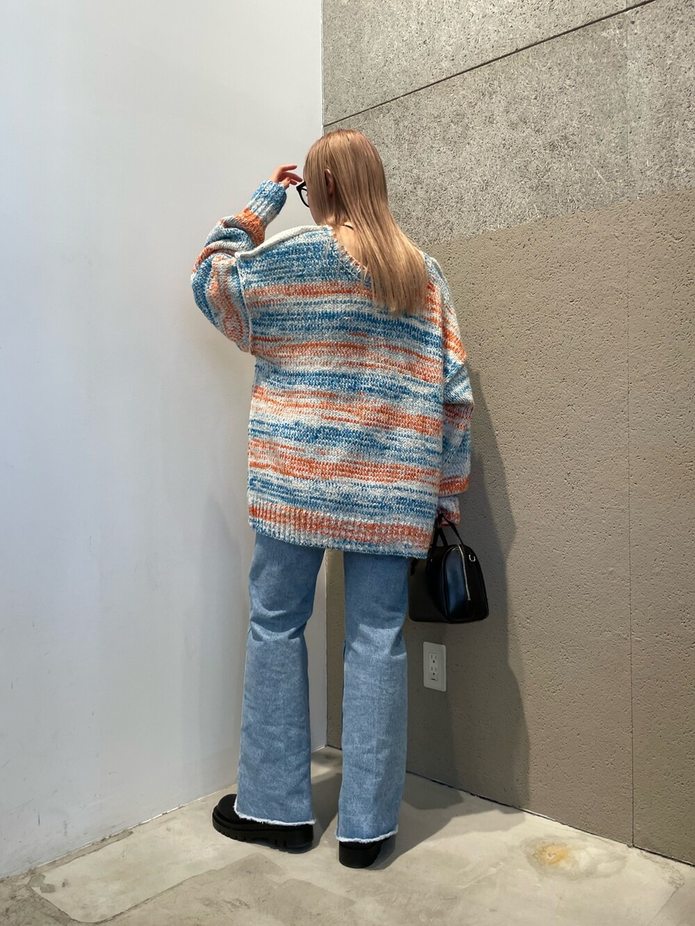 ホワイト系のカーディガン/ボレロ、ブラック系のバッグ、ブルー系のデニムパンツを着用したレディースの秋コーディネートの2枚目の写真