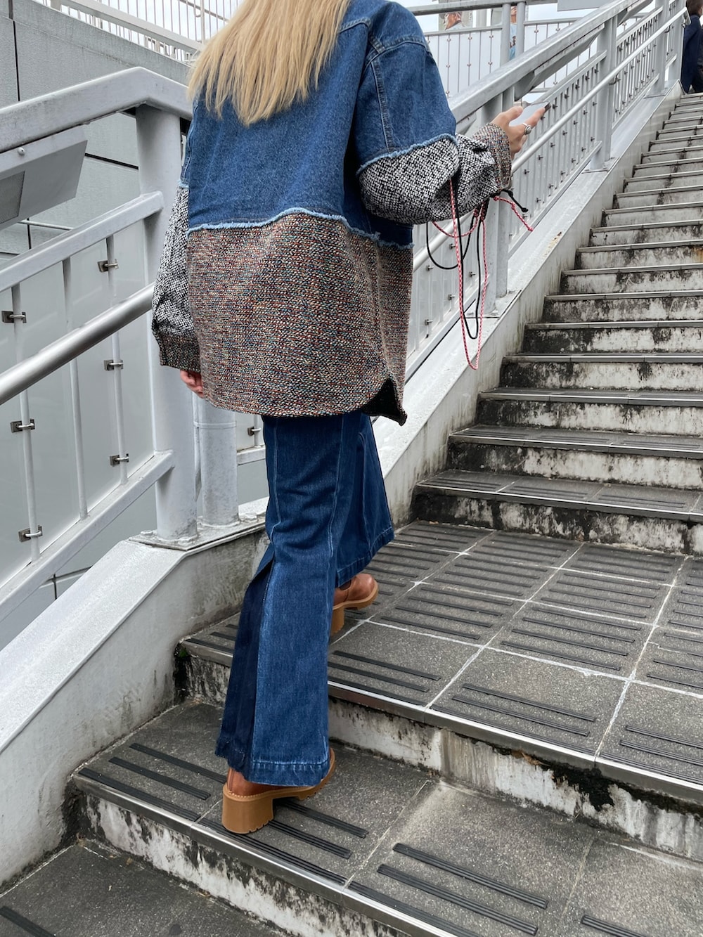 ブルー系のデニムジャケット、ブルー系のデニムパンツ、パープル系のショルダーバッグを着用したレディースの秋コーディネートの3枚目の写真