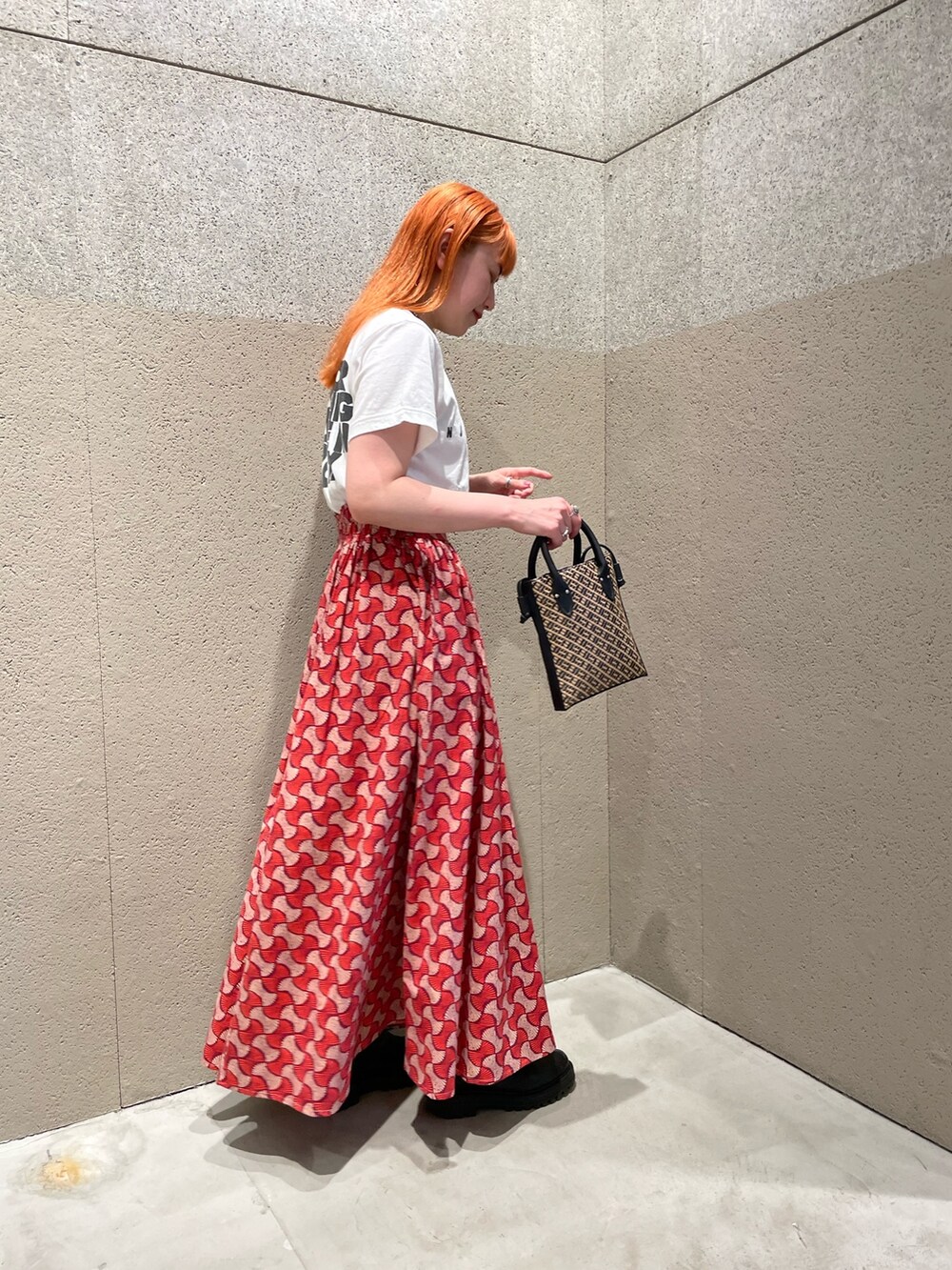 ホワイト系のTシャツ/カットソー、レッド系のスカート、ブラック系のトートバッグを着用したレディースの夏コーディネートの2枚目の写真