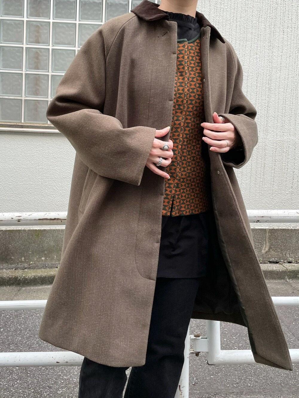 グリーン系のステンカラーコート、ブラウン系のベスト、ブラック系のシャツ/ブラウスを着用したレディースの秋コーディネートの3枚目の写真