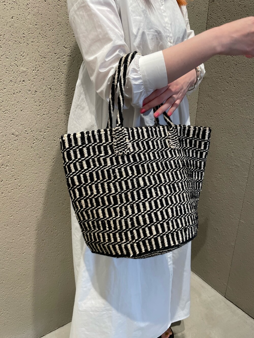 ホワイト系のワンピース、ブラック系のかごバッグ、ブラック系のサンダルを着用したレディースの夏コーディネートの5枚目の写真