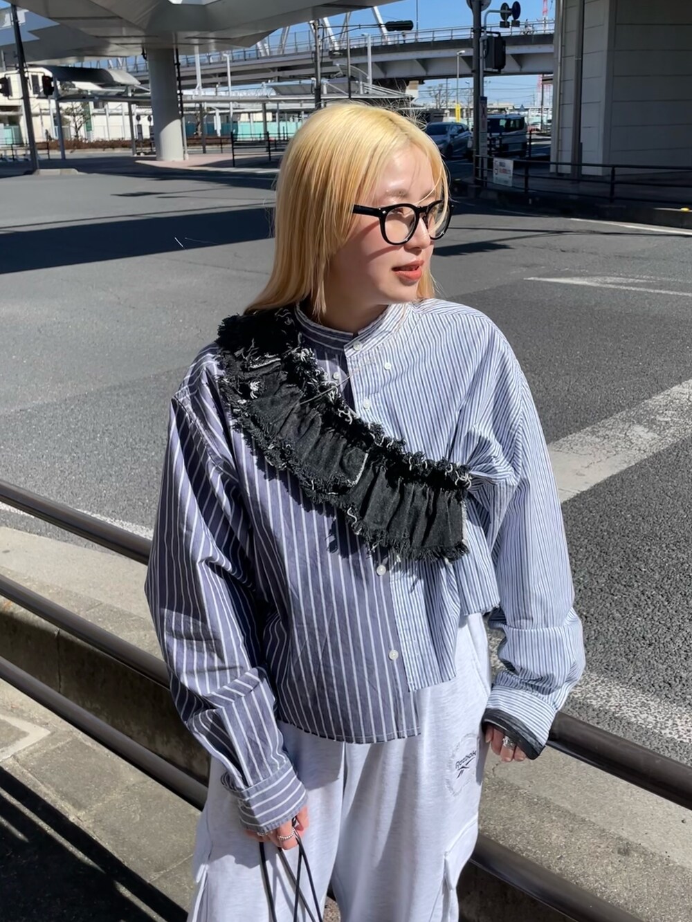 ブルー系のシャツ/ブラウス、ブラック系のデニムスカート、グレー系のパンツを着用したレディースの春コーディネートの4枚目の写真