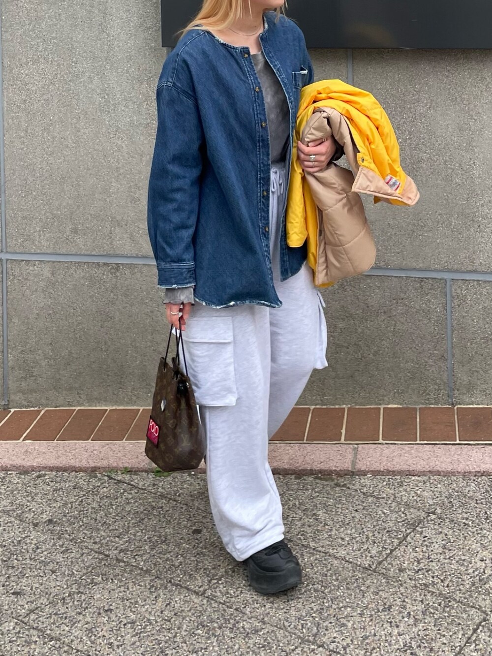 ブラック系のスニーカー、グレー系のパンツを着用したレディースの春コーディネートの2枚目の写真