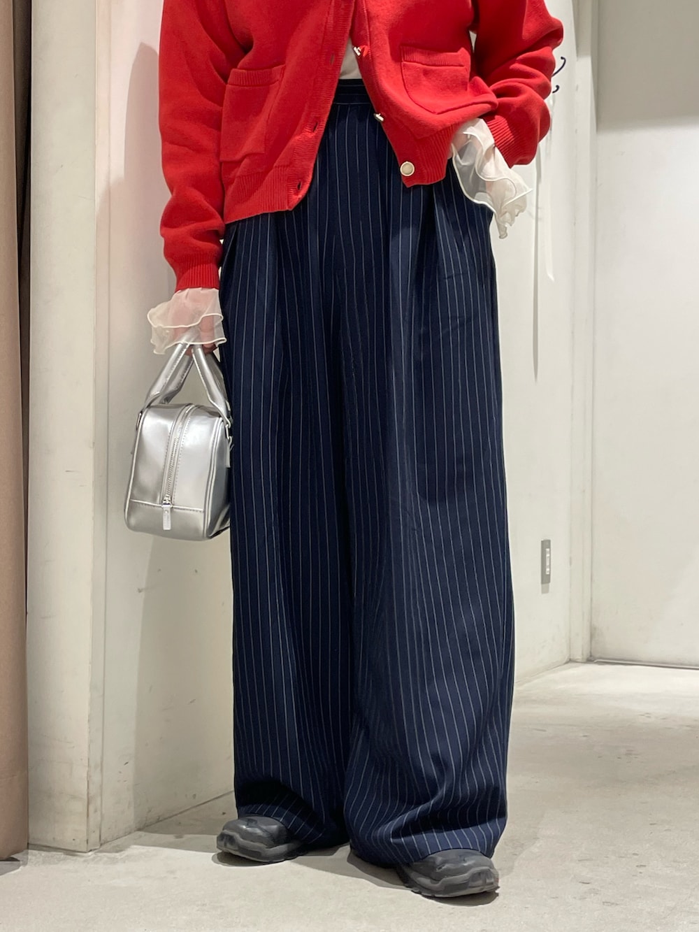 レッド系のカーディガン/ボレロ、イエロー系のTシャツ/カットソー、ブルー系のスラックスを着用したレディースの冬コーディネートの5枚目の写真