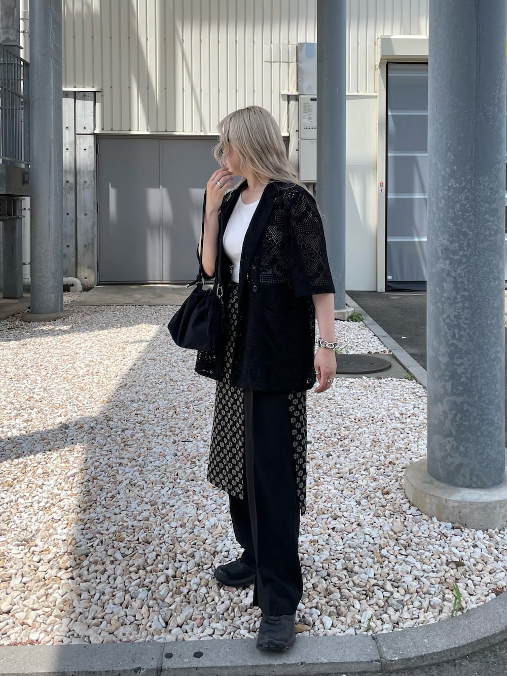 ブラック系のテーラードジャケット、ブラック系のスカート、ブラック系のショルダーバッグを着用したレディースの夏コーディネートの3枚目の写真