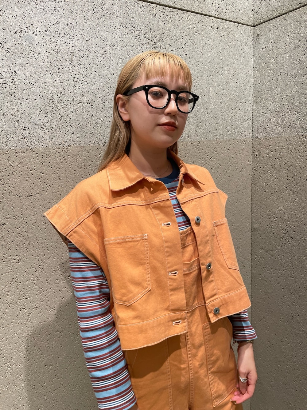 オレンジ系のデニムジャケット、オレンジ系のサロペット/オーバーオール、ブルー系のワンピースを着用したレディースの秋コーディネートの2枚目の写真