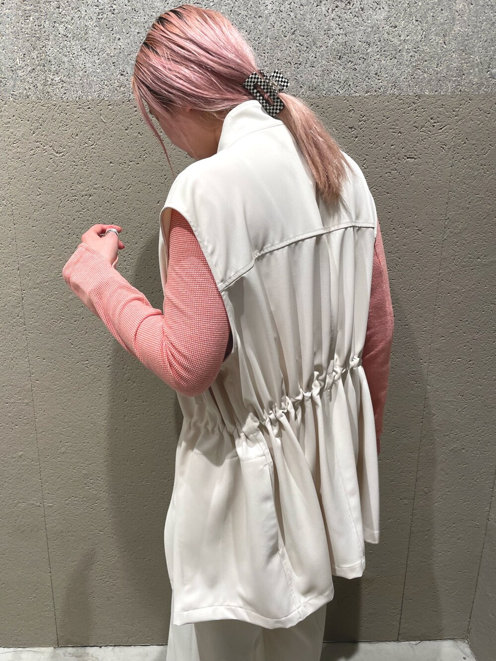 ホワイト系のベスト、オレンジ系のTシャツ/カットソー、ホワイト系のスラックスを着用したレディースの春コーディネートの3枚目の写真