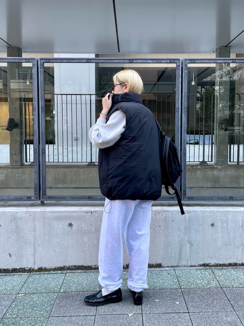 ブラック系のダウンベスト、ホワイト系のニット/セーター、グレー系のスウェットパンツを着用したレディースの冬コーディネートの6枚目の写真