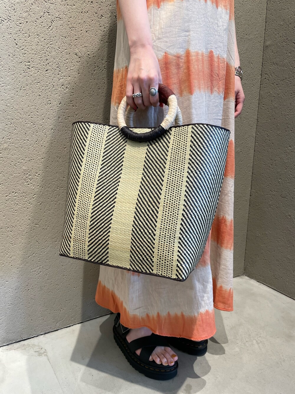 オレンジ系のワンピース、ベージュ系のTシャツ/カットソー、ブラック系のかごバッグを着用したレディースの春コーディネートの5枚目の写真