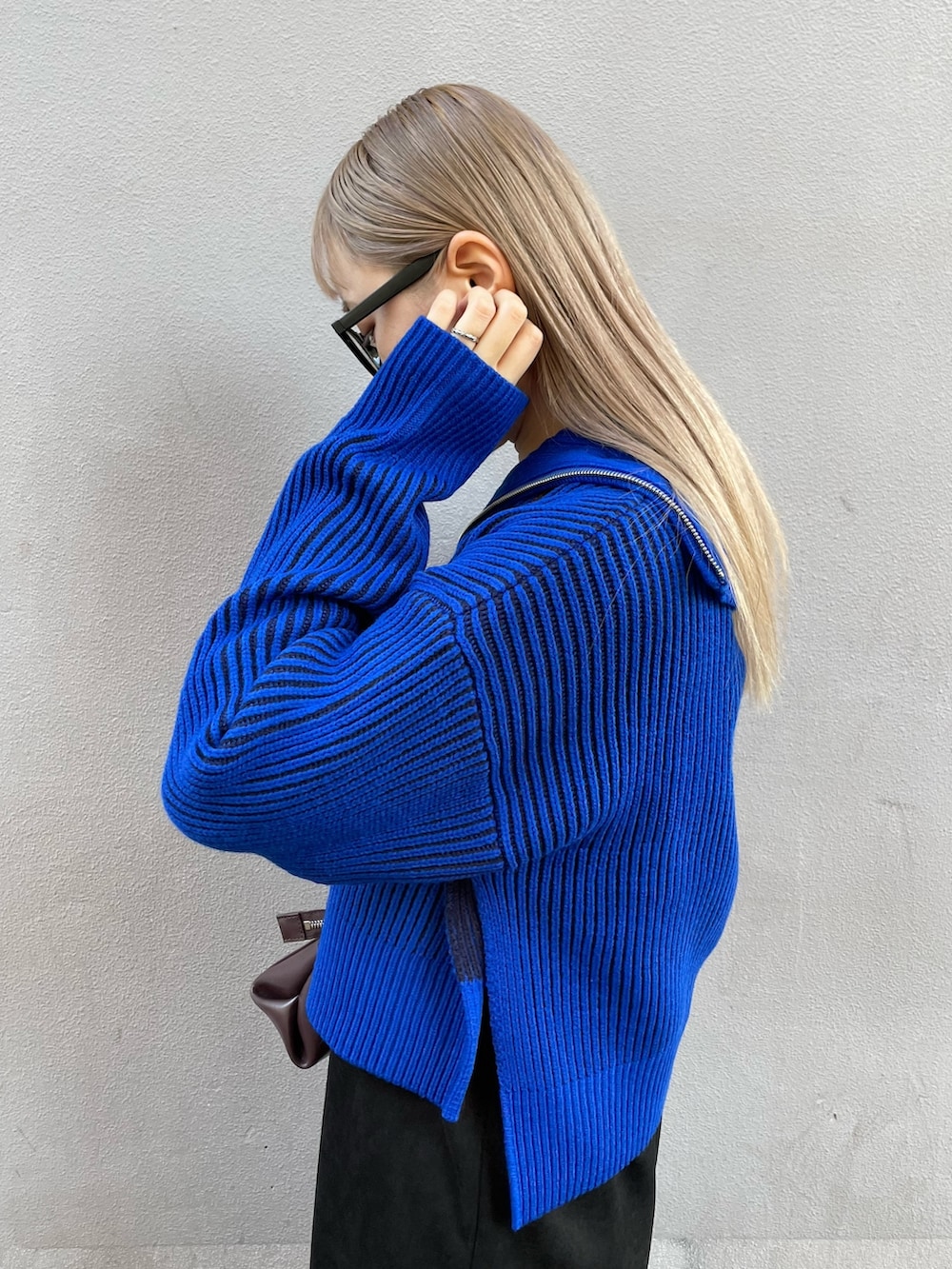 ブルー系のニット/セーター、ブラック系のワンピース、ブラック系のブーツを着用したレディースの秋コーディネートの6枚目の写真