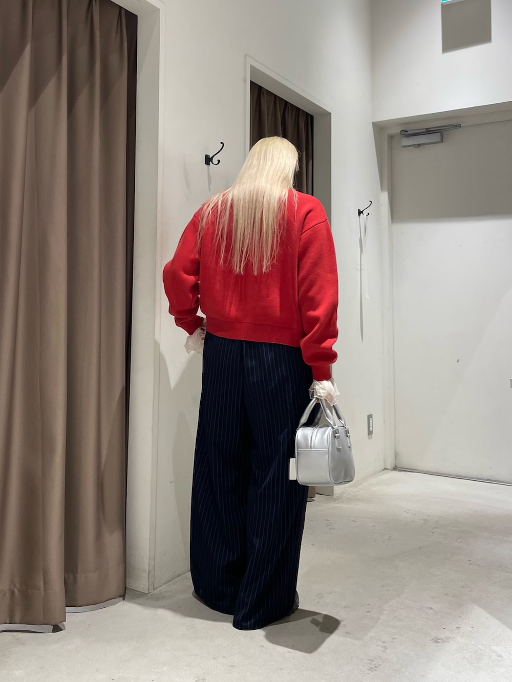 レッド系のカーディガン/ボレロ、イエロー系のTシャツ/カットソー、ブルー系のスラックスを着用したレディースの冬コーディネートの8枚目の写真