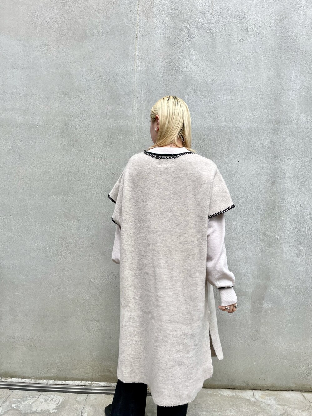 ホワイト系のニット/セーター、ブラック系のデニムパンツ、ブラック系のブーツを着用したレディースの秋コーディネートの5枚目の写真